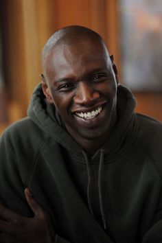 a smiling man in a black hoodie with his arms crossed