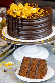 a chocolate cake sitting on top of a white plate next to a slice of cake