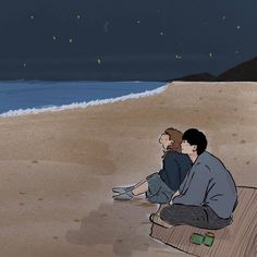 two people sitting on the beach at night