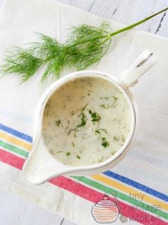 a white bowl filled with soup on top of a striped napkin next to a green plant