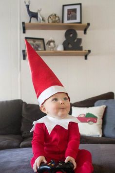 a baby sitting on top of a couch wearing a red and white elf hat