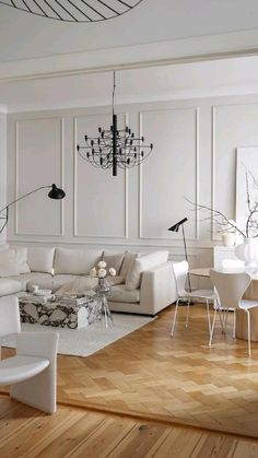 a living room filled with furniture and a chandelier hanging from the ceiling over a wooden floor