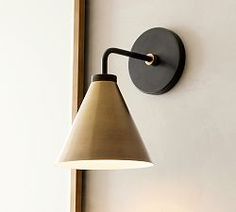 a wall light mounted on the side of a white wall next to a mirror and lamp