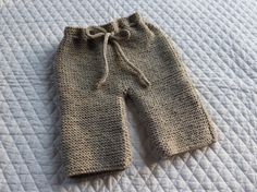 a knitted pair of pants sitting on top of a bed