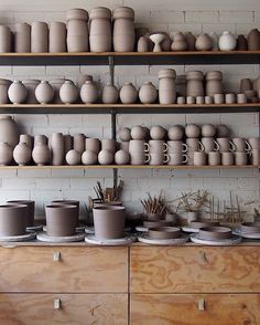 many clay pots and bowls are on shelves