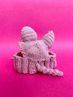 a knitted hat sitting on top of a pink surface