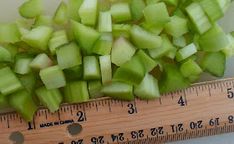 chopped up green apples sitting on top of a wooden ruler