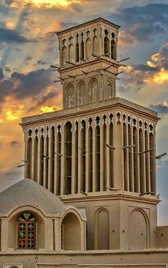 a tall building with a clock on it's side and clouds in the background