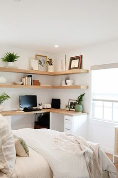 a bedroom with white walls and open shelving above the bed, along with a computer desk