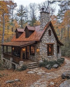 a stone house with a red roof in the woods