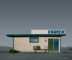 a small building with a sign that reads church on the roof and two chairs in front of it