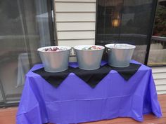 three buckets are sitting on top of a purple table cloth with black ribbon around it