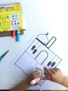 a child's hand writing on a piece of paper with crayons next to it