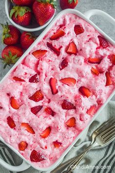 strawberry ice cream in a white dish with strawberries on the side next to it