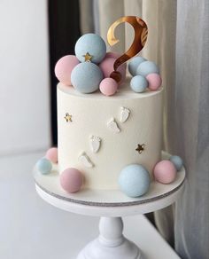 a white cake with pink, blue and gold decorations on it's top tier