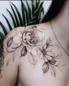 the back of a woman's shoulder with flowers and leaves tattoo on her chest