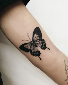 a black and white butterfly tattoo on the arm