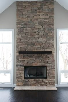 an empty living room with a stone fireplace