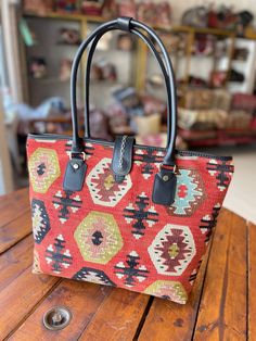 a handbag sitting on top of a wooden table next to a metal object in the background