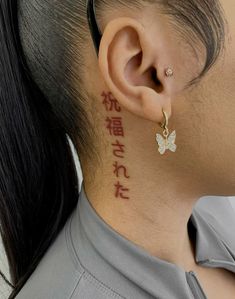 a woman with a butterfly tattoo on her neck and behind her ear is the word love written in chinese