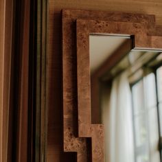 a mirror that is on the side of a wall next to a window with curtains