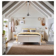 a bedroom with white walls and wooden floors, along with a beige rug on the floor