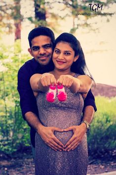 a man and woman standing next to each other with their hands in the shape of a heart