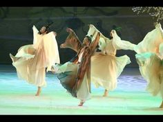 four women in white dresses are dancing on stage