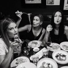 three women sitting at a table with plates of food and drinks in front of them