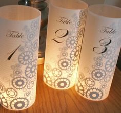 three wine bottles are sitting on a table with paper lanterns in the shape of numbers