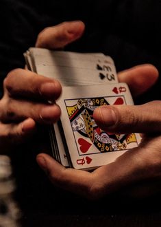 two hands holding playing cards on a table