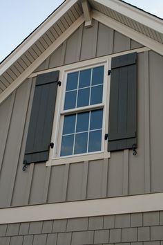 the side of a house with two windows and shutters