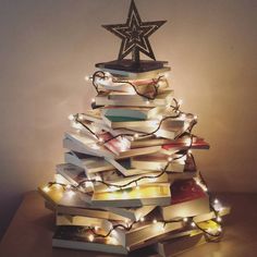 a christmas tree made out of books with lights around it and a star on top