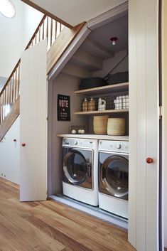 a washer and dryer in a small room with stairs leading up to the second floor