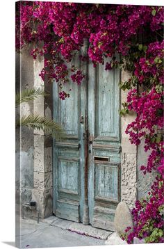 an old wooden door with pink flowers growing over it