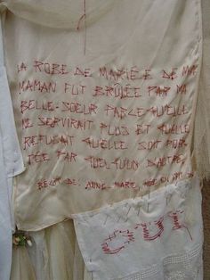 a piece of cloth with writing on it hanging from a clothes line next to other pieces of clothing