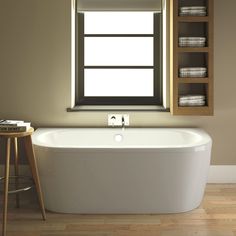 a white bath tub sitting under a window next to a wooden table and stools