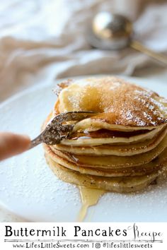 a stack of pancakes covered in syrup on top of a white plate with a spoon