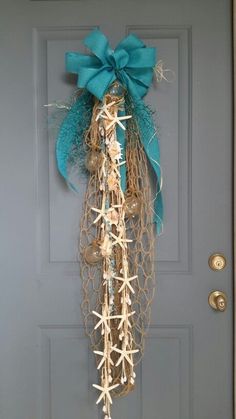 a door with a blue bow hanging from it's side and sea shells on the front