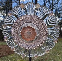 a glass plate sitting on top of a metal stand in front of some grass and trees