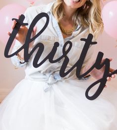 a woman in a white dress holding up a sign with the word party written on it