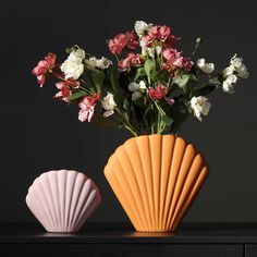 two vases with flowers in them sitting on a table next to each other,