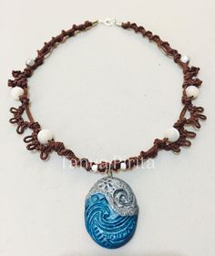 a blue and white beaded necklace with an ocean theme pendant hangs from a brown cord