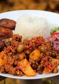 a white plate topped with meat, rice and veggies on top of a table