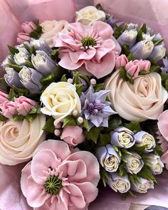 a bouquet of pink, white and purple flowers on top of a bed of fabric