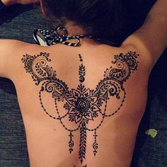 the back of a woman's body is decorated with hendix and flowers