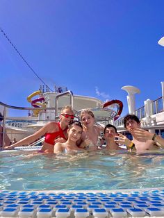 four people in a pool posing for a photo on the deck of a cruise ship