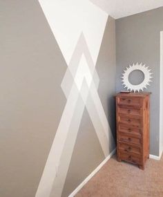 a room with a dresser, mirror and wall painting