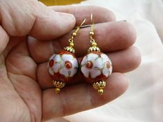 (Internal #EE602-4)  You are bidding on this pair of one bead, 20 mm round RED with pink white flowers CLOISONNÉ bead DANGLE EARRINGS with gold tone filigree caps and bead accents, on gold tone French wire earrings.  This is exactly the pair of earrings you will get.   CLOISONNÉ EARRINGS, CHINA:  Here's how a cloisonné bead is made: A copper body is hammered and welded.  Then wire "cells" (where the word "cloisonné" came from) are formed and soldered on the copper body.  Preliminary enamel filli Red Flower Earrings For Pierced Ears, Pink Round Jewelry With Bead Caps, Round Beaded Earrings With Bead Caps As Gift, Round Beaded Earrings With Bead Caps For Gifts, Nickel Free Rose Gold Round Flower Earrings, Pink Round Beaded Earrings, Rose Gold Nickel-free Round Flower Earrings, Rose Gold Round Nickel-free Flower Earrings, Nickel-free Round Pink Flower Earrings