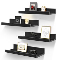 three black shelves with pictures, frames and clocks on them in the shape of bookshelves